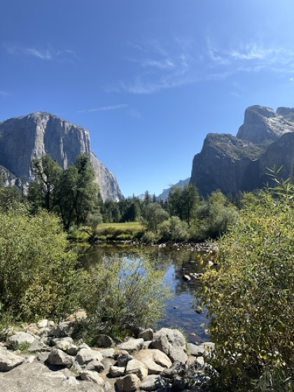 A granite valley with sheer cliffs on both sides, a still river below and willows along the bank.